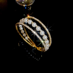 Macro detail of multilayer gold bracelet with pearls and shimmering pave crystals