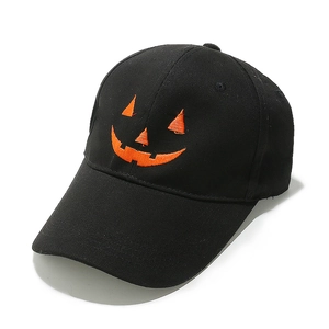 Close-up of orange pumpkin face embroidery on a black vintage cotton baseball cap