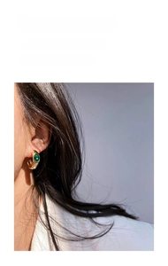 Close-up of vintage gold-plated C-shape hoop earring featuring a green oval emerald zircon