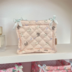 Detailed macro view of pink quilted storage bag featuring cute rabbit prints and blue bows