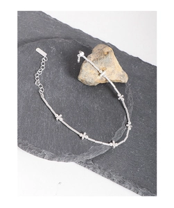 Macro shot of S925 sterling silver bar and bead bracelet resting on natural stones
