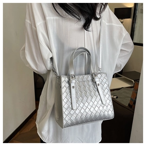 Detail of silver woven texture tote bag with fashion bag tag and metallic finish straps