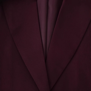 Gros plan du revers bordeaux d'une veste de tailleur chic avec texture de tissu détaillée