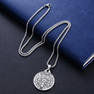 Silver St. Benedict medal necklace with woven steel chain on a professional dark background