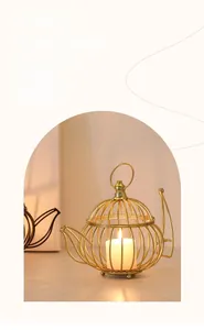 Golden teapot-shaped metal hollow candle holder with warm lit candle inside