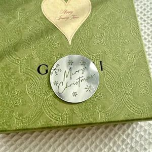 Macro shot of silver Merry Christmas metal cupcake topper on vintage green embossed gift box