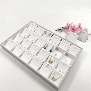 Detailed view of 24-compartment jewelry display tray with grey frame and white pads