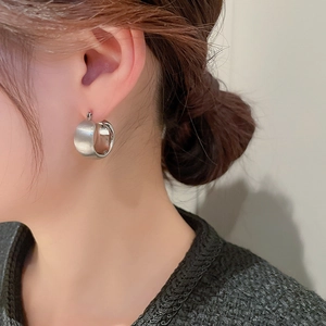 Close-up of a silver minimalist wide geometric hoop earring on a model's ear