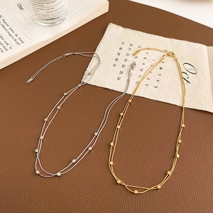 Close-up of double-layered titanium steel necklace with square pendants on vintage book