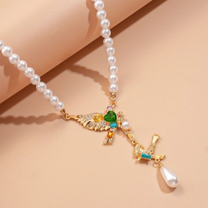 Close-up of golden bird pendant with colorful heart crystals and teardrop pearl