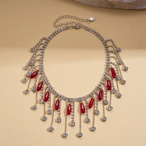 Détail d'un collier à pampilles argenté avec strass rouges en goutte et fermoir mousqueton