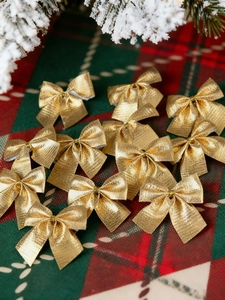 Close-up of 12 pack champagne gold textured Christmas bows on festive red plaid background