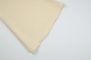 Close-up of high-quality edge stitching on a beige chiffon lace cardigan garment