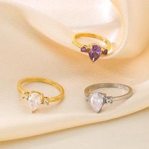 Elegant stainless steel rings with teardrop zircon stones on premium silk background
