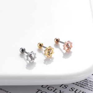 Detail of three stainless steel flower cartilage studs in silver, gold, and rose gold finishes