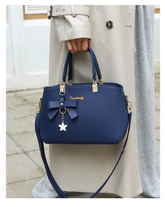 Detail of dark blue faux leather handbag featuring a bow ornament and star pendant