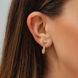 Close-up of golden liquid droplet earrings with irregular minimalist metallic design