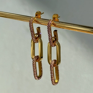 Close-up of gold linked drop earrings with purple crystals and polished mirror finish