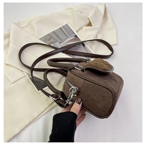 Close-up of brown suede handbag featuring plush fleece flap and silver metal hardware