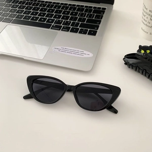 Close-up of black cat-eye sunglasses with dark lenses and matching cat hair clips on a desk