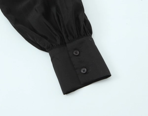 Close-up of black shirt cuff with pleated fabric and double button closure detail