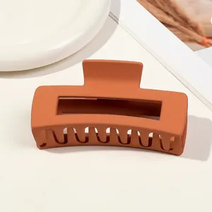 Detail of large matte orange hair claw clip with hollow rectangle design on ceramic dish