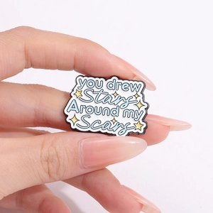 Inspirational enamel pin with text You Drew Stars Around My Scars and yellow stars