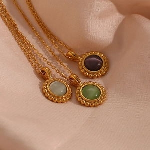 Close-up of three gold sunburst pendant necklaces with opal stones on pink silk