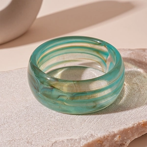 Close-up of geometric acrylic bangle featuring teal and brown marble resin texture