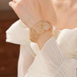 Close-up of beige amber-patterned acrylic wide elastic bracelet on female wrist