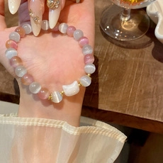 Dettaglio del bracciale con perle occhio di gatto rosa e bianche e ciondolo a forma di gatto