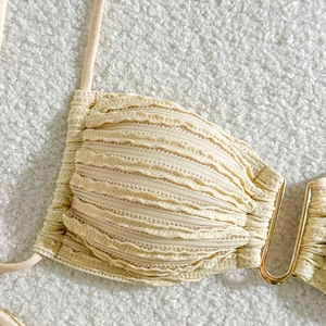 Detailed close-up of beige textured bikini top featuring a gold U-shaped metal buckle