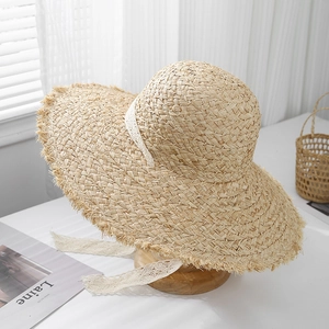 Close-up of raffia straw sun hat featuring a delicate white lace ribbon and frayed brim