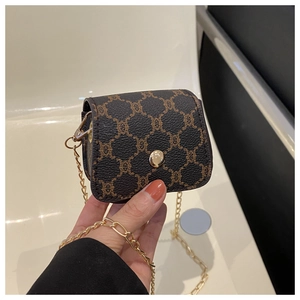 Detail of mini crossbody bag with dark brown pattern print and gold chain strap