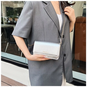 Silver metallic shoulder bag with gold chain strap styled on a grey blazer outfit