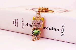 Detail shot of golden lucky cat keychain featuring sparkling rhinestones and a green gem