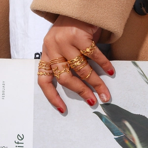 Detail of gold stackable rings including star cutouts and braided textures on a model