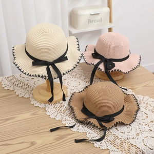 Close-up of woven straw sun hats featuring wavy edges and elegant black ribbon bows