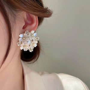 Detail of floral stud earrings with white petals and pearls worn by a model