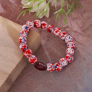 Detail of beaded bracelet with red blue marbled beads and a brown football charm