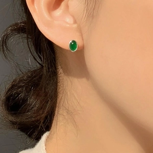 Close-up of green agate oval stud earring with silver setting worn on model's ear