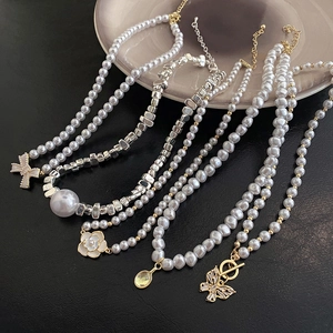 Baroque pearl necklaces with butterfly and camellia pendants on black leather background