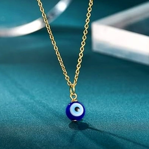 Macro shot of gold stainless steel chain with blue evil eye amulet pendant detail