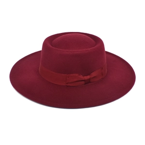 Detail of burgundy wool fedora hat showing satin bow ribbon and texture on white background