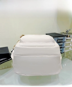 Detail view of white minimalist nylon backpack showing zipper compartments and matte texture