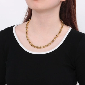 Gros plan d'un collier doré avec anneaux et design de nœuds porté par un modèle