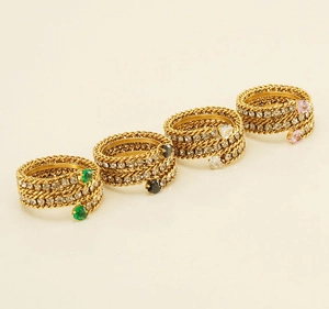 Detailed view of layered 18k gold snakeskin rings with colorful teardrop gemstones