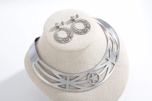 Detail of silver metallic choker and star earrings set on a beige display mannequin