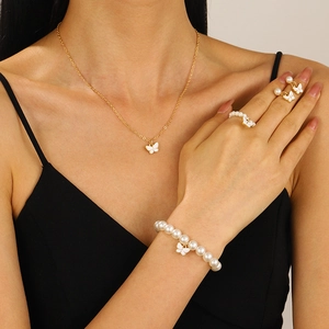 Conjunto de joyas doradas con mariposas blancas y perlas que incluye collar y pulsera