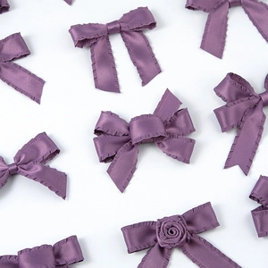 Détail de nœuds en ruban plissé violet avec centre de rose sur un fond blanc épuré